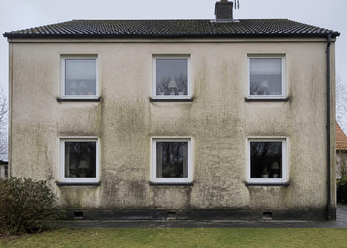 Villafasad före fasadtvätt – tydlig grön algpåväxt och smuts på putsen